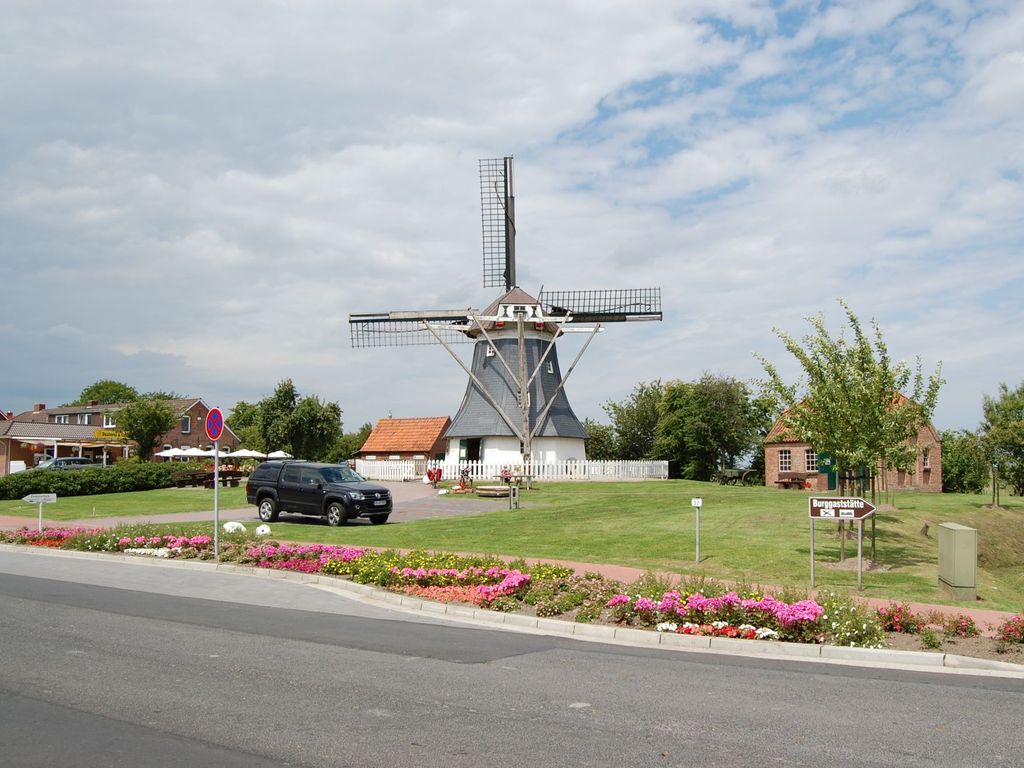 Mühle in Werdum mit Rasenfläche und Blumen im Vordergrund