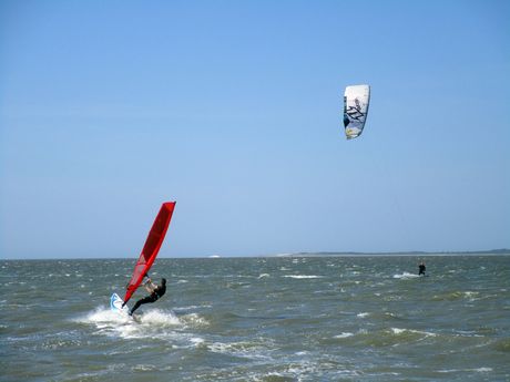 Ein Kitesurfer und ein Windsurfer im Wasser vor Dornumersiel